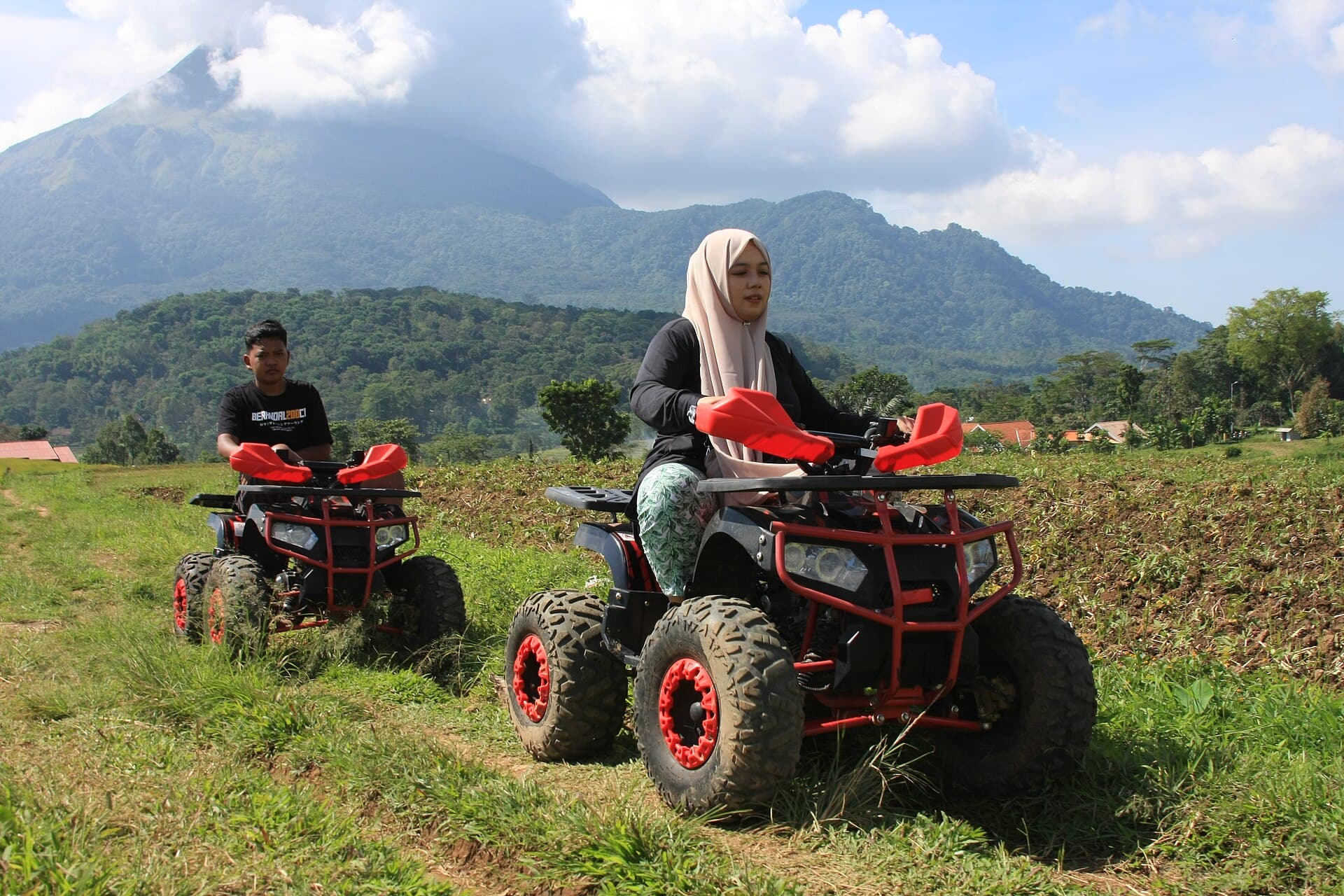 Twee quads rijden over een veld met bergen op de achtergrond
