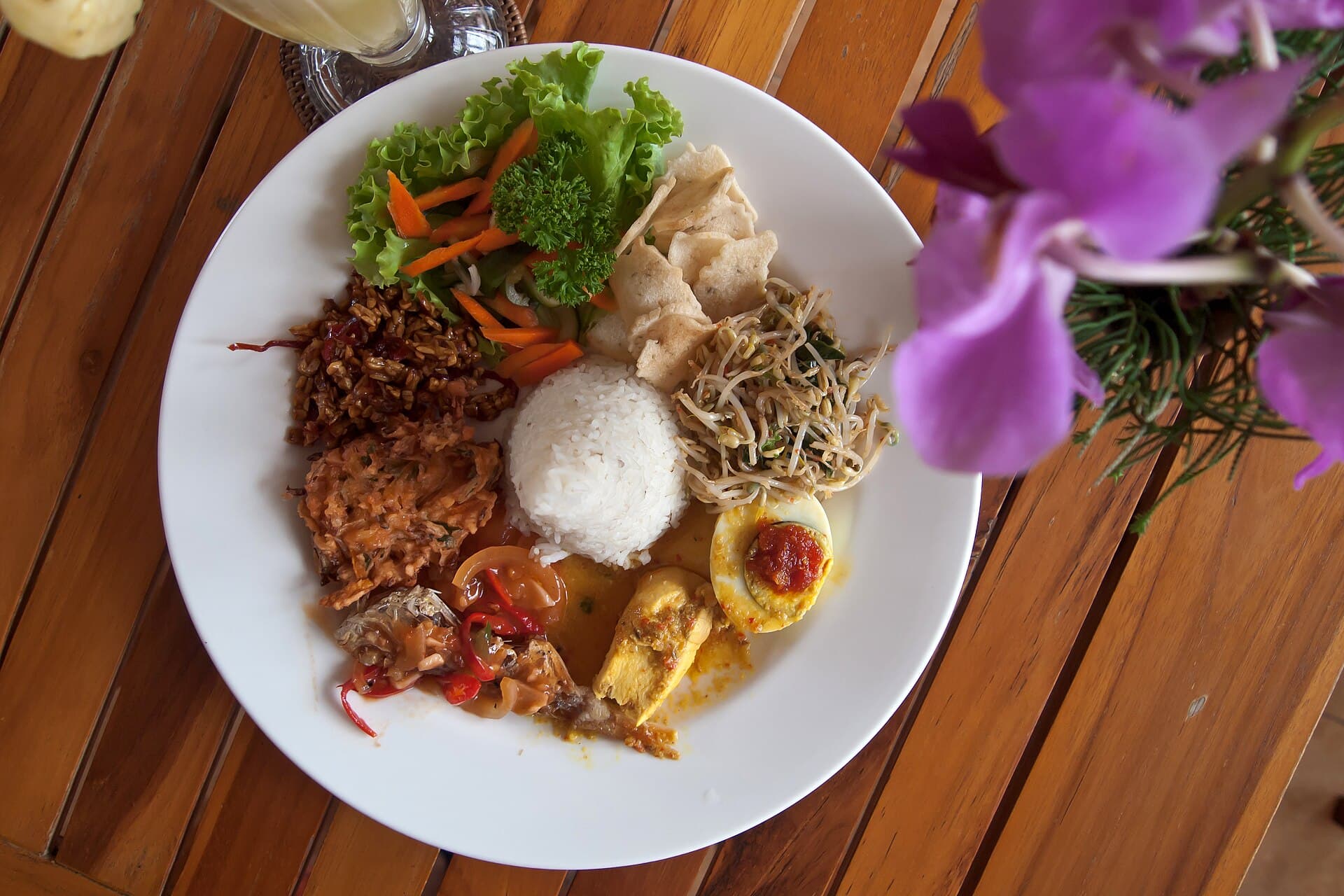 Bord nasi campur met rijst, groenten, sate en sambal